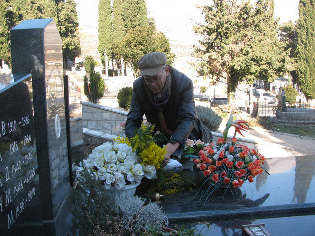 Rade Aleksić polaže cvijeće na grob svog sina Srđana. (Foto: Srna)