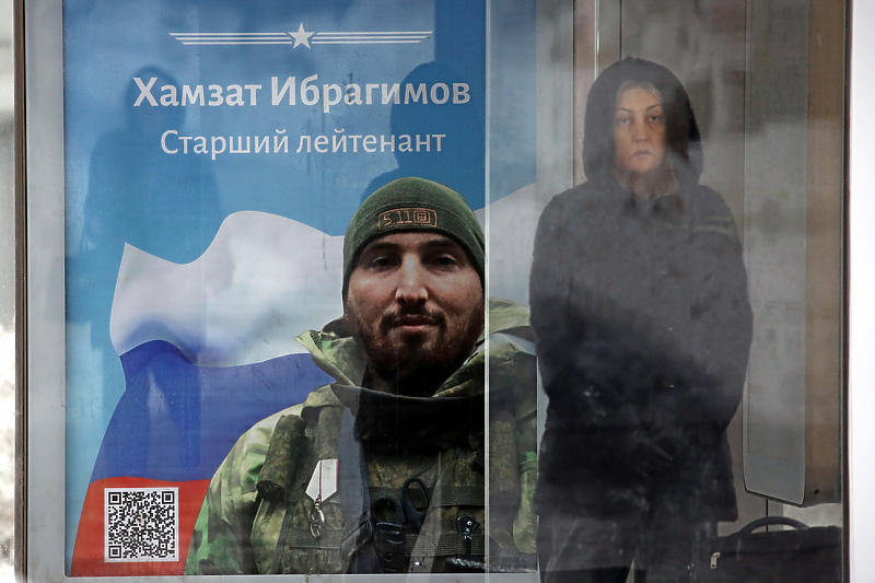 Žena čeka na autobuskoj stanici u blizini plakata koji prikazuje ruskog vojnika (Foto: EPA-EFE)
